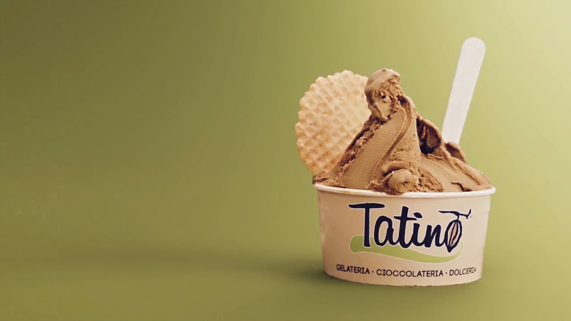 Un bicchiere Tatino di gelato alla nocciola con il cialdone, su un fondo verde oliva