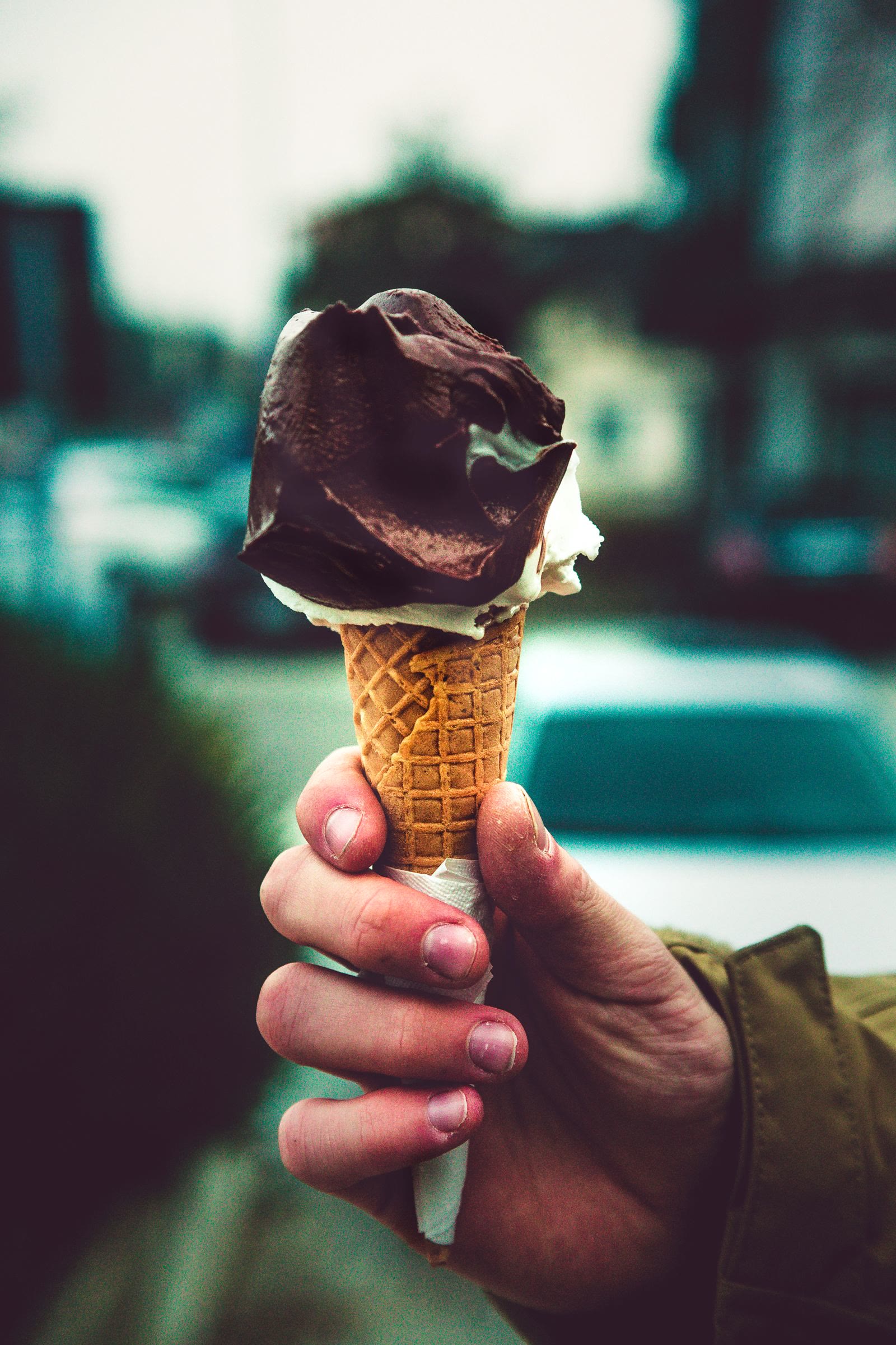 Un cono con gelato al cioccolato tenuto in mano