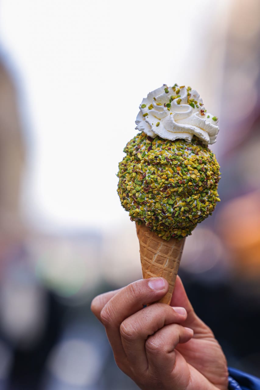 Un cono con gelato al pistacchio tenuto in mano
